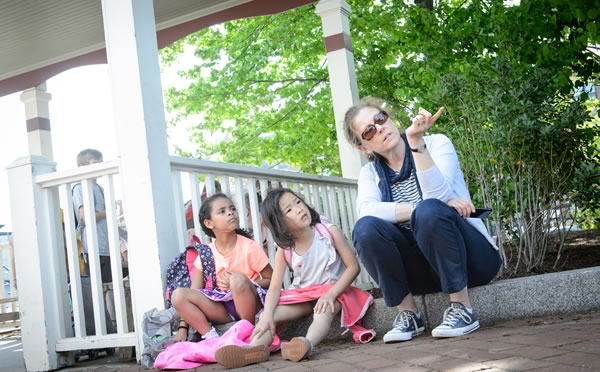 A woman sitting with two girls on a curb outside